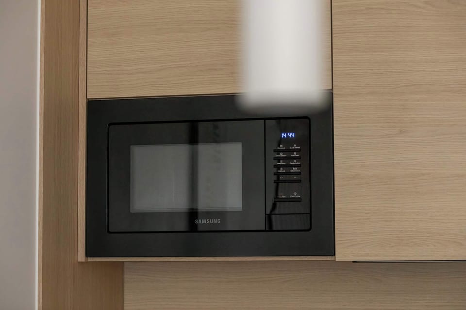 Close-up of a modern built-in microwave oven surrounded by light wood cabinetry. This feature highlights the kitchen's modern conveniences.
