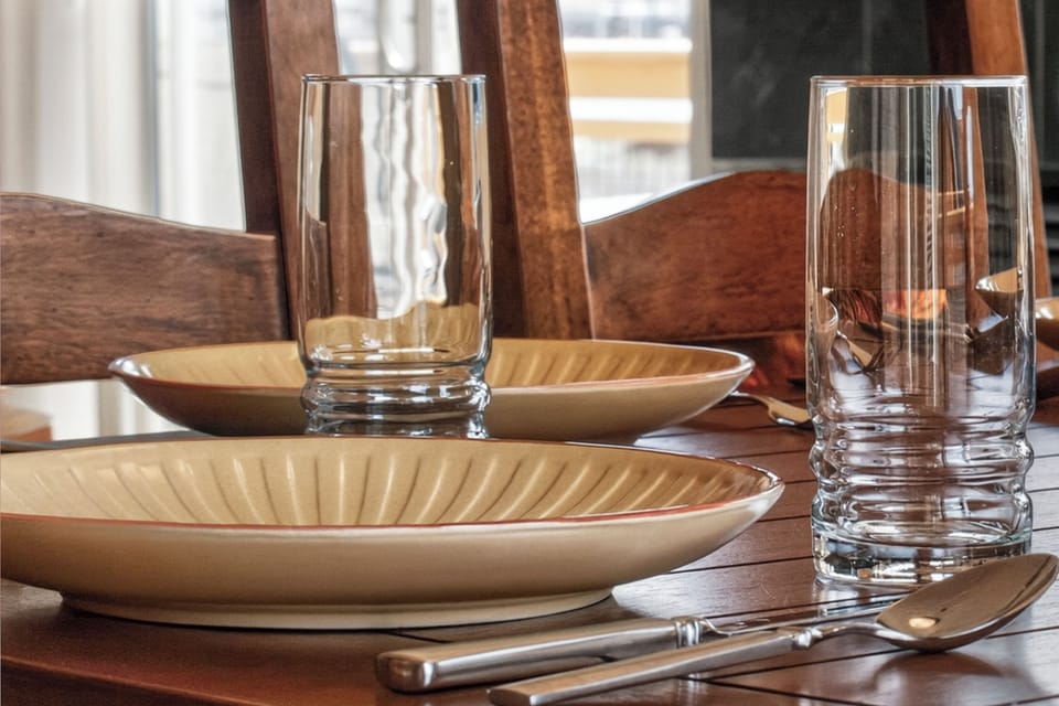 Your dining table awaits with elegant ceramic dishes and crystal glasses, perfectly set for memorable meals together.