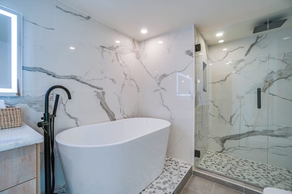 Slip into the elegant soaking tub or refresh under the rainfall shower in this spa-inspired bathroom, where marble walls and modern fixtures create your private sanctuary.
