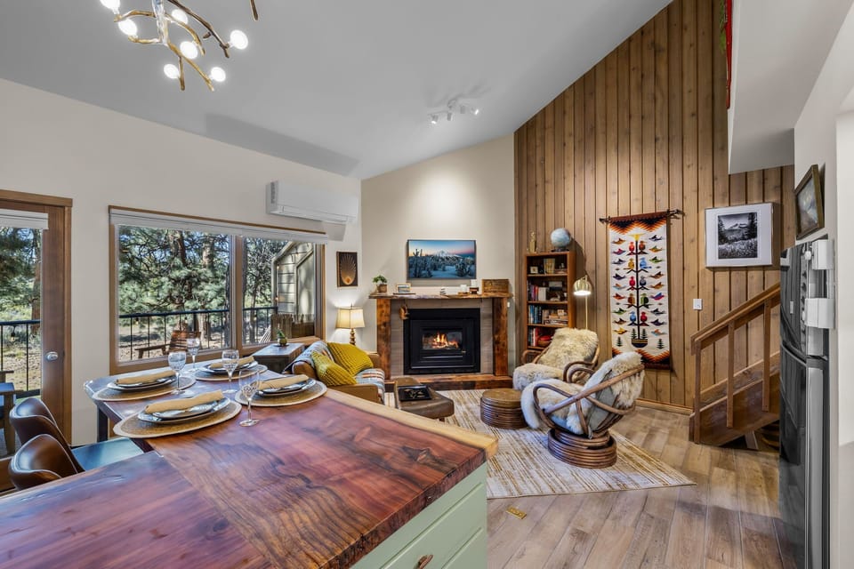Gather around this inviting open-concept space where your group can cook, dine, and unwind by the fireplace—all surrounded by natural wood warmth and mountain views.