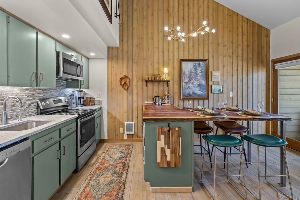 Your retreat welcomes you with a fully-equipped kitchen featuring modern appliances and a stylish wood island perfect for shared meals, all bathed in natural light from vaulted ceilings.