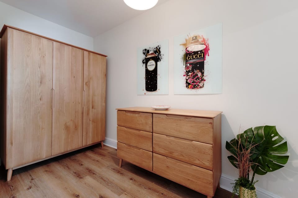 The second bedroom features two single beds, a chest of drawers, and a wardrobe for clothing storage