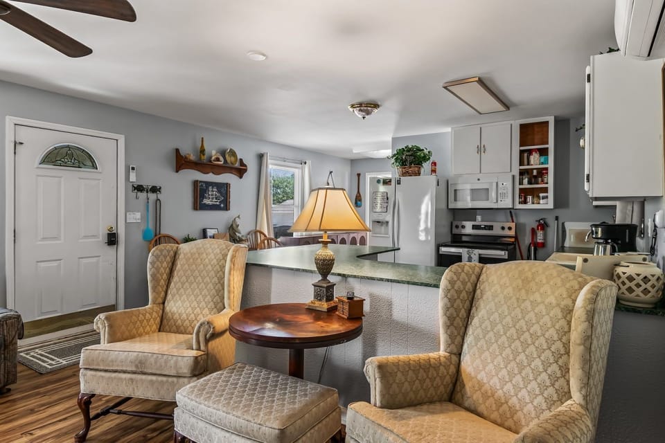 Kitchen and dining nook with white cabinetry, green countertops, and high-backed bar chairs at the counter