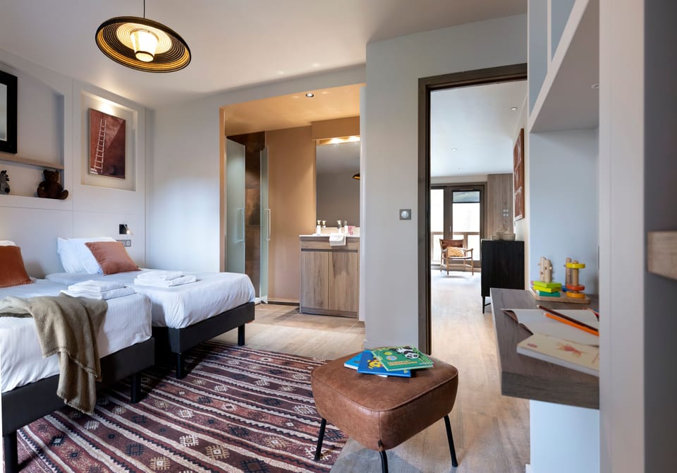 Twin bedroom with direct access to an en-suite glass shower — four bathrooms serve the apartment