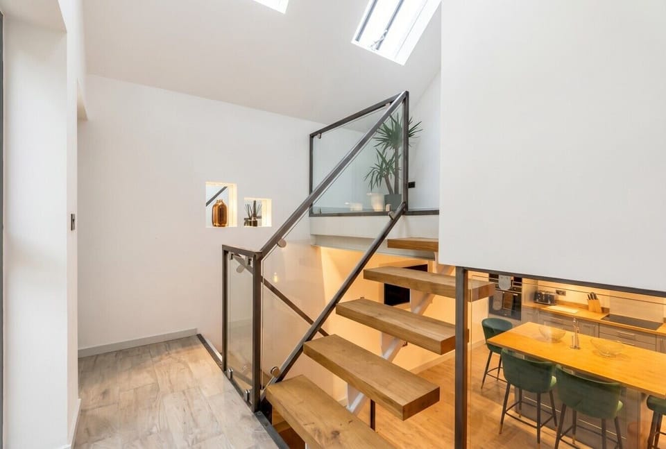 Soaring vaulted ceilings and a floating oak staircase flood the interior with skylight.