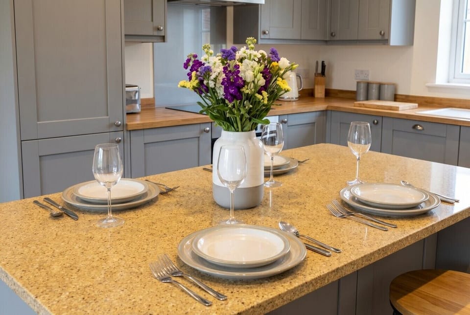 A welcoming kitchen island set for four with fresh flowers and oak worktops.