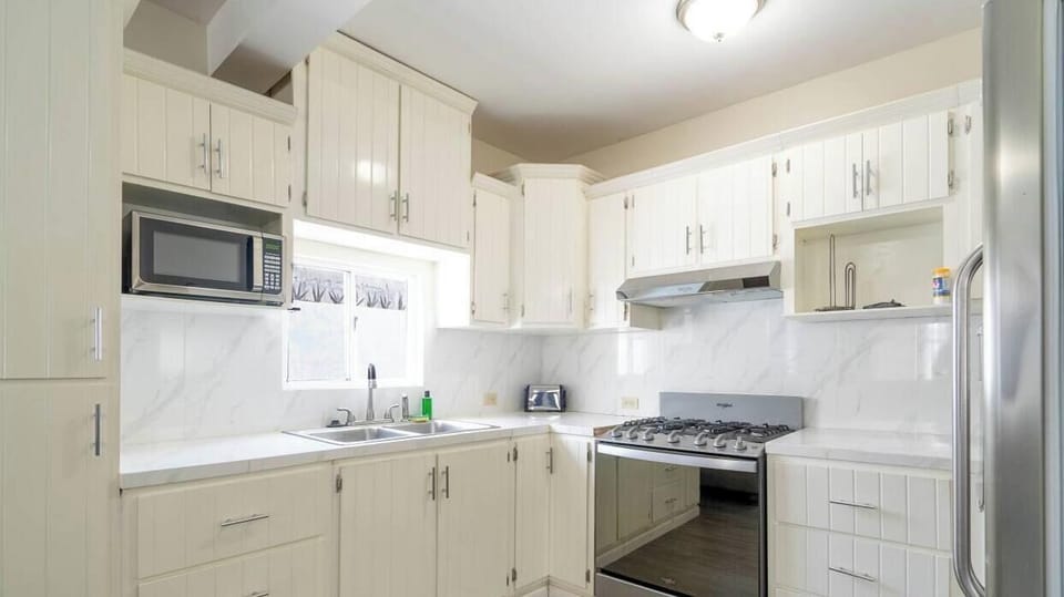 Alternate view of the gourmet kitchen highlighting custom cabinetry, granite countertops, and fully stocked appliances — toaster, coffee maker, and blender included .