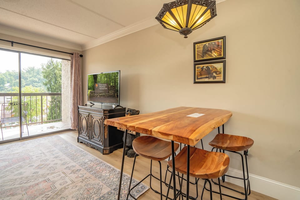 This inviting living and dining space features a stunning live-edge wood table where you can share meals or morning coffee. Natural light fills the room, while your private balcony offers peaceful views of the surrounding greenery.