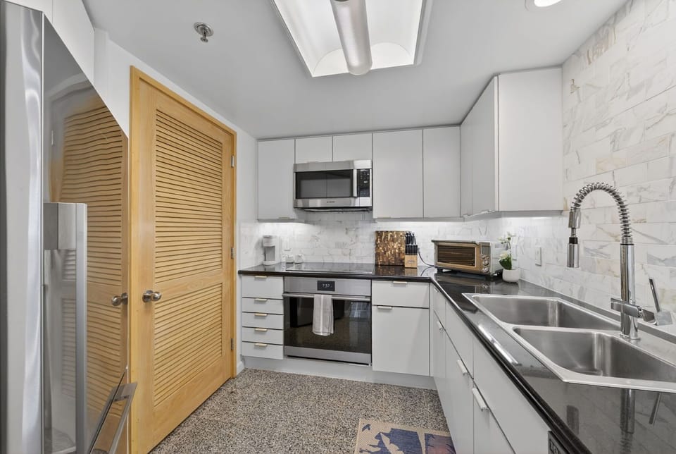 Prepare island meals in the refreshed kitchen with sleek appliances and stone counters.