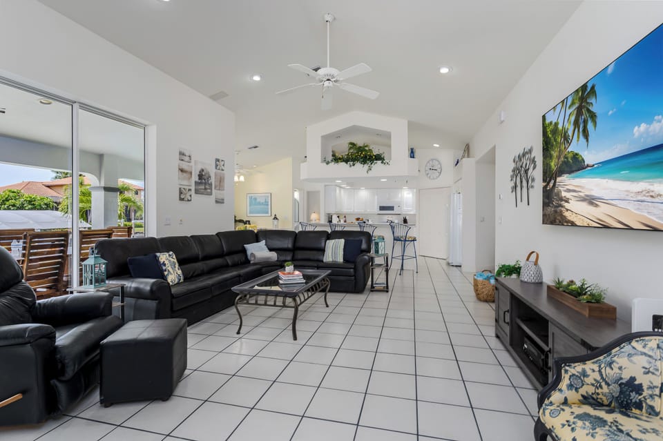 Relax in your spacious, light-filled living room with vaulted ceilings, plush leather seating, and vibrant tropical artwork that sets a vacation mood from the moment you arrive.