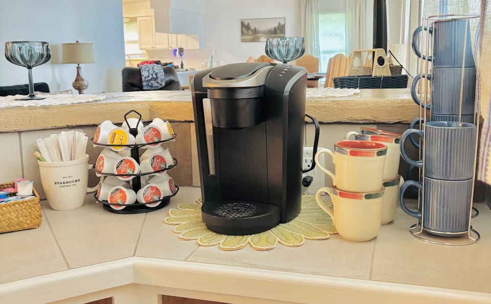 Coffee bar stocked with coffee K-cups, a variety of tea bags, sugar, & creamer.