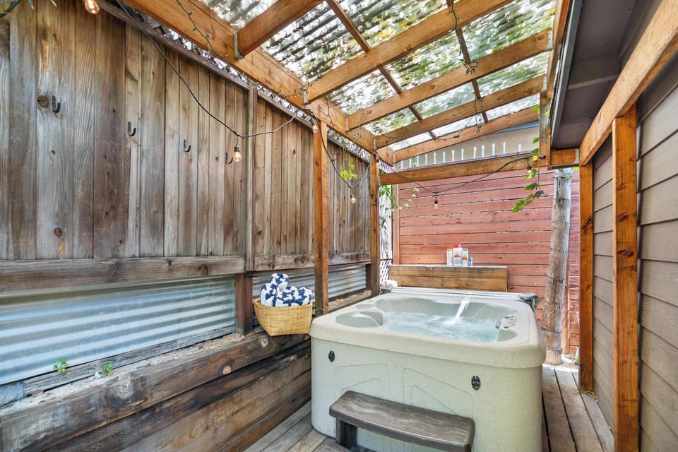 Private Hot Tub — 4-Person Spa with Bubbling Water, Wood Pergola with Corrugated Polycarbonate Roof, String Lights, Weathered Wood Fence Walls with Robe Hooks & Wicker Towel Basket