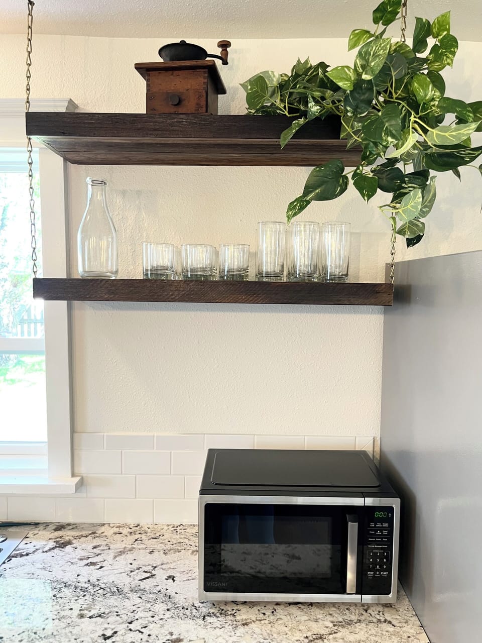 Tall and short glassware located on the open shelving along with water carafes..