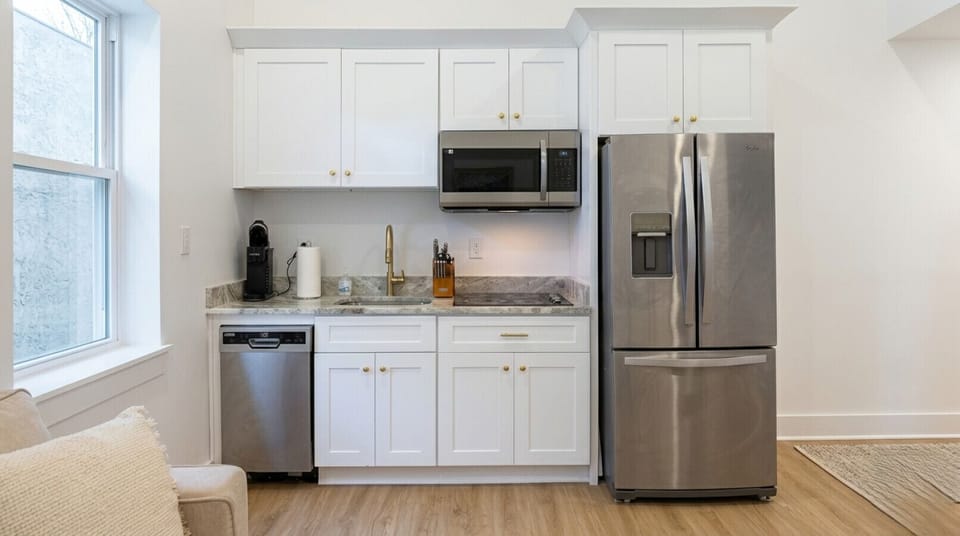 Stylish fully equipped kitchen featuring stainless steel fridge, microwave, dishwasher, and sleek cabinetry ideal for vacation rentals and extended stays.