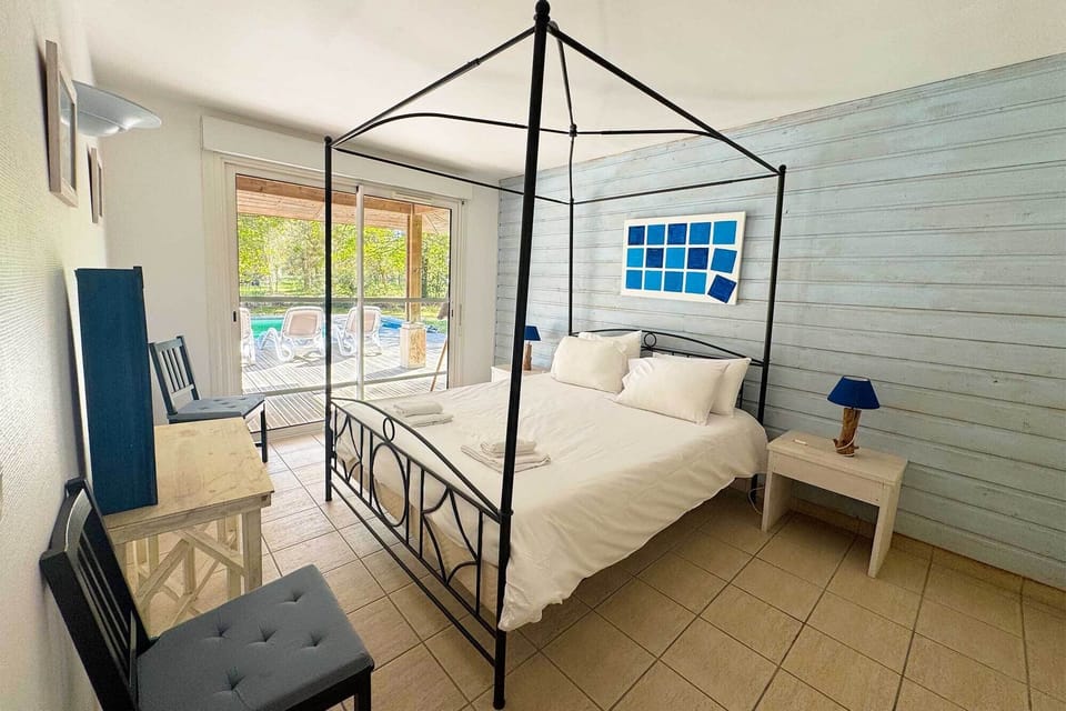 Double bed with terrace-facing windows — wake up to pine trees and garden light before a day at the beach.