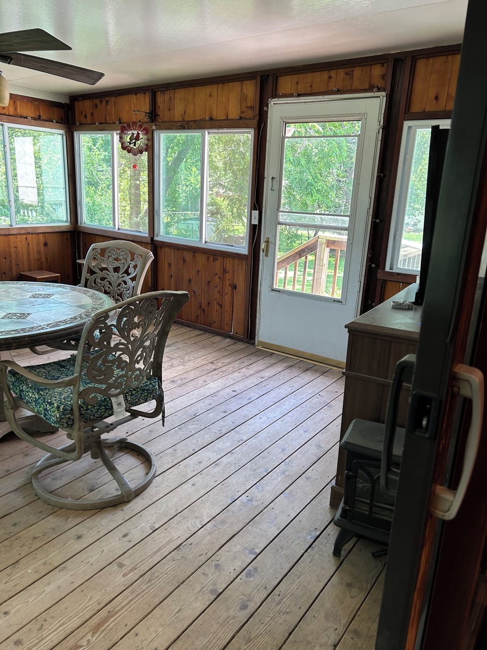 Screened porch with ceiling fan, table for four, and television