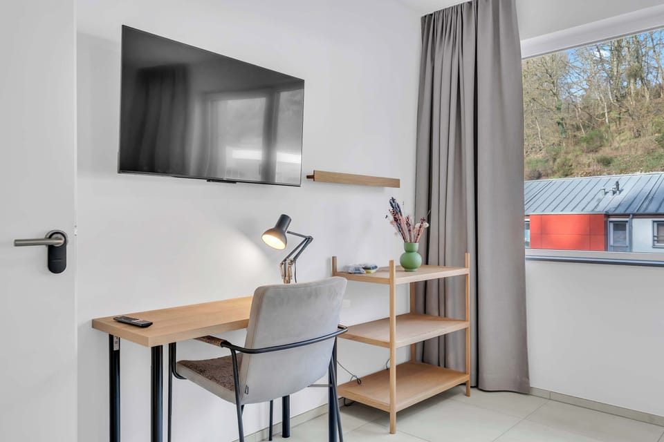 Dedicated workspace with desk, Smart TV, storage shelf, and large window, ideal for remote work or planning your day
