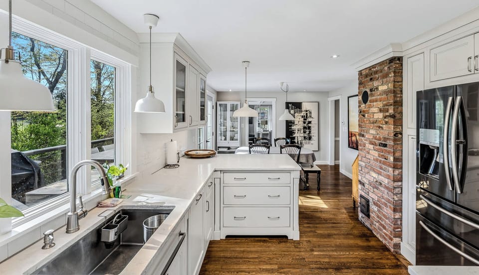 Open-concept kitchen with exposed brick, center island, and modern stainless steel appliances