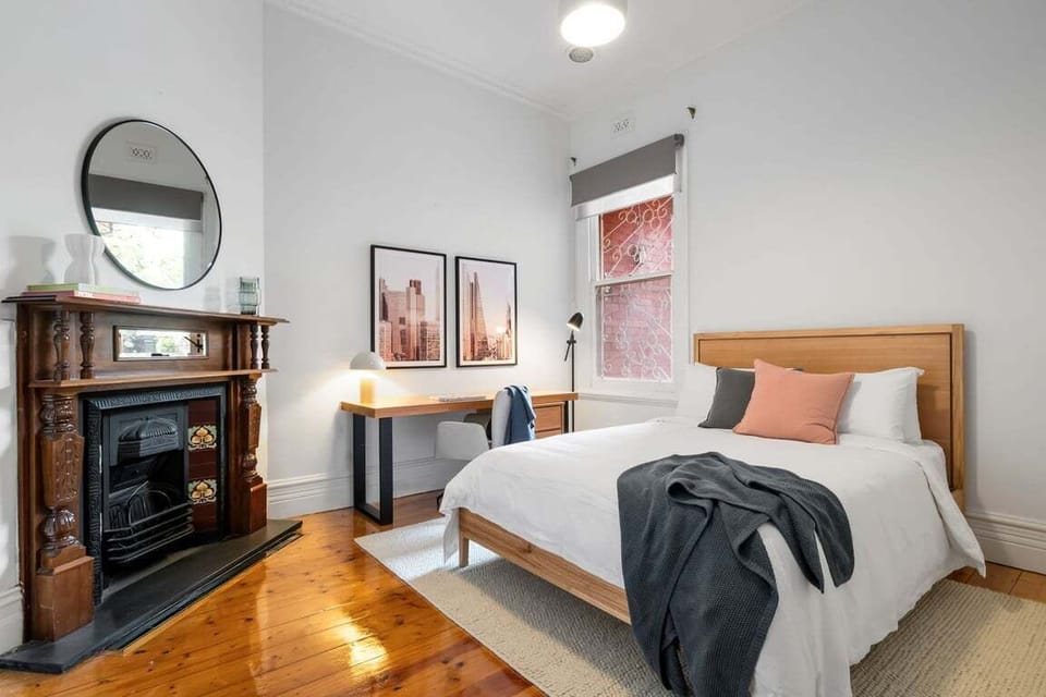 Bright, modern bedroom with a wooden bed, cozy fireplace, and warm natural light.