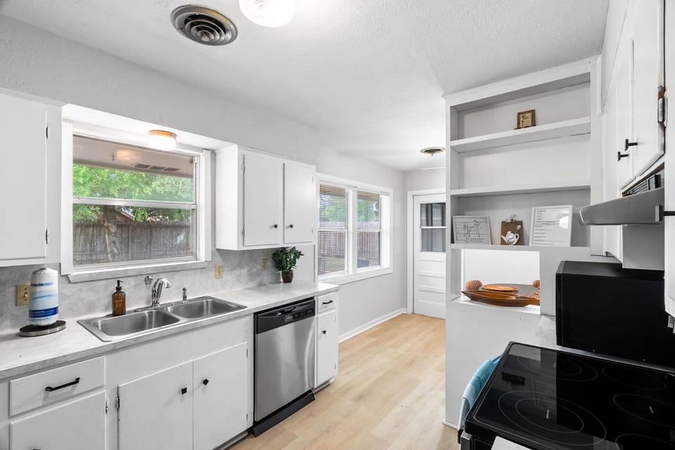 Bright kitchen featuring a stainless steel dishwasher, double sink, and plenty of prep space.