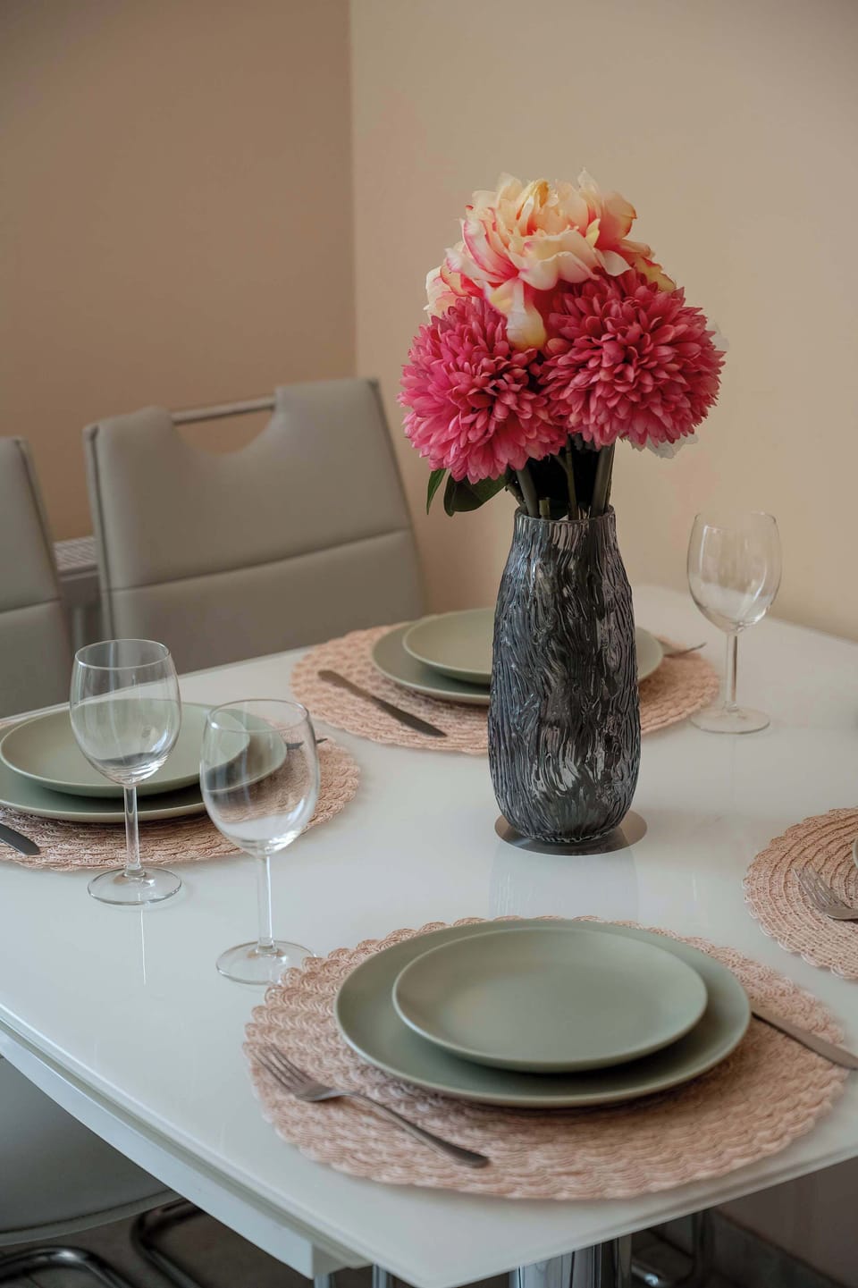 A neatly set dining table with plates and flowers. The arrangement feels warm and ready for a shared meal.