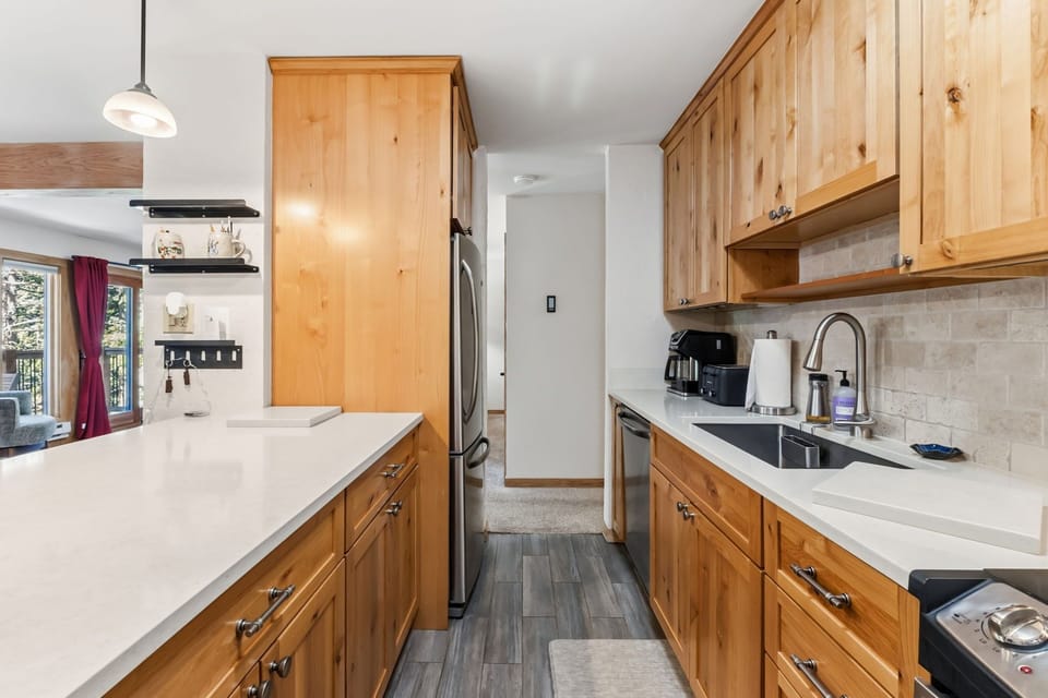 Your spacious kitchen features warm wood cabinetry, sleek countertops, and modern stainless appliances, perfect for preparing meals or enjoying morning coffee in your home away from home.