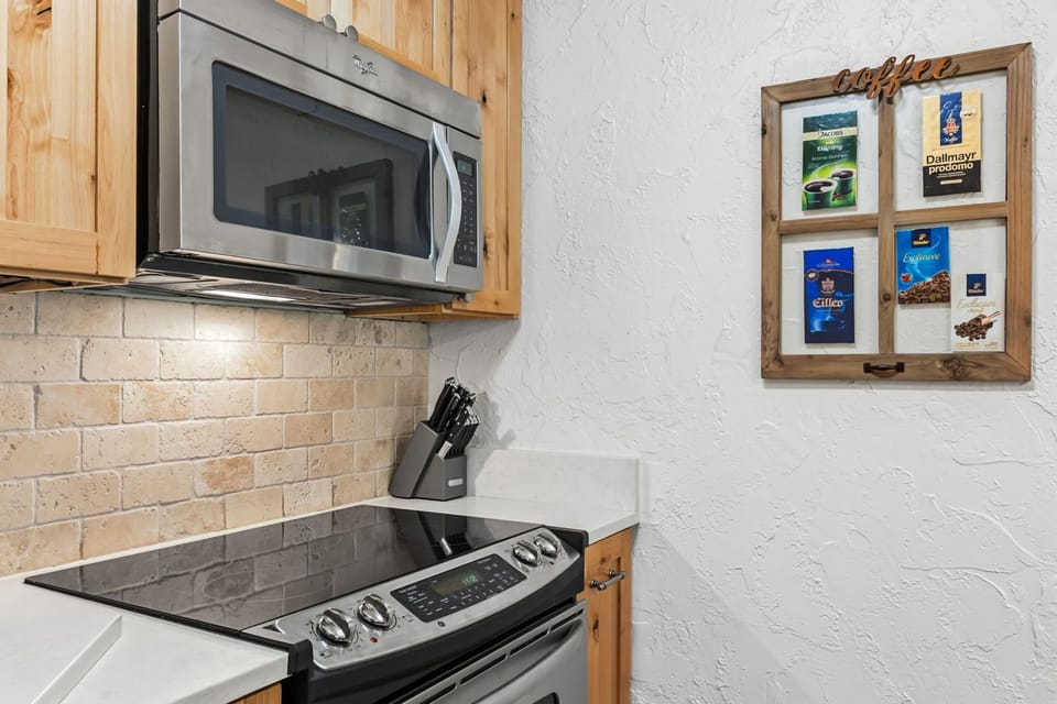 Your kitchen comes equipped with modern appliances, including a built-in microwave and smooth-top stove, perfect for preparing meals during your stay. Enjoy your morning coffee in style with the charming coffee station display.