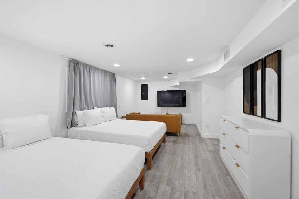 The final bedroom showcases a pair of queen beds & a sitting area with smart TV​