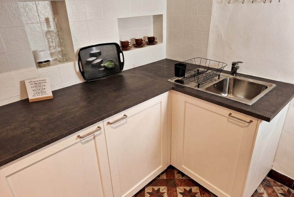 Tiled kitchen corner with prep space and classic mosaic floor.