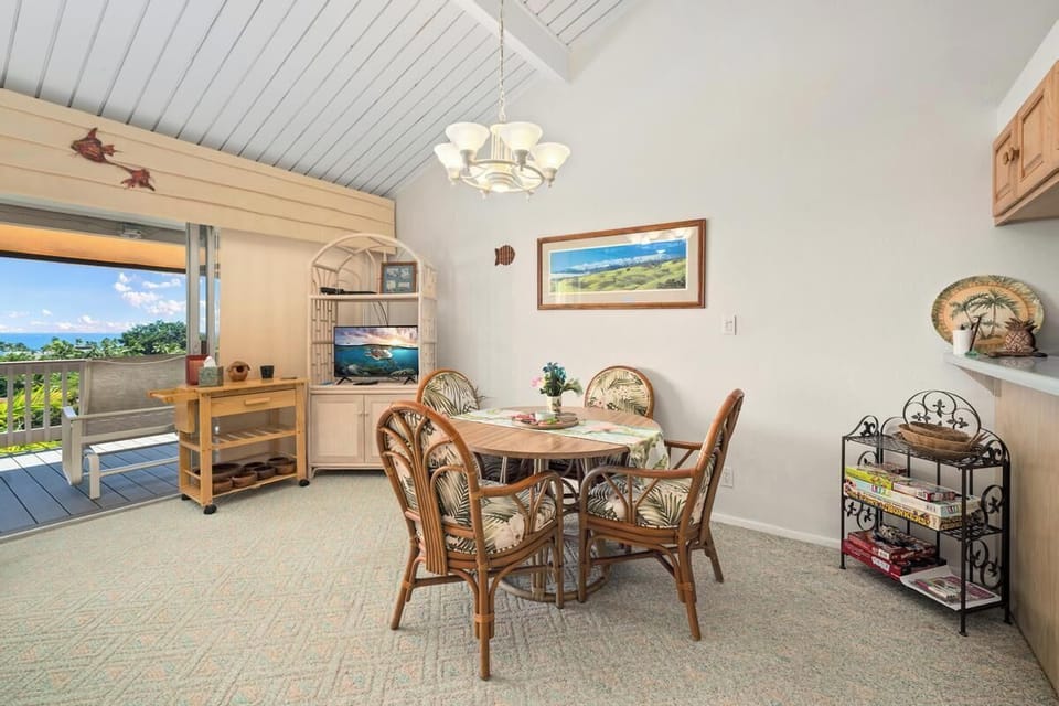 Gather around this welcoming dining table with vaulted ceilings and enjoy meals with ocean views framing your experience through the open lanai doors.