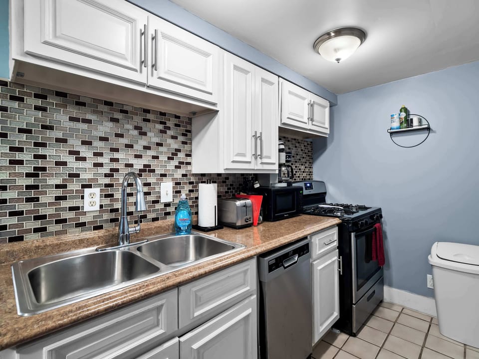 Kitchen w/ mosaic tile backsplash, stainless appliances & plenty of counter space.
