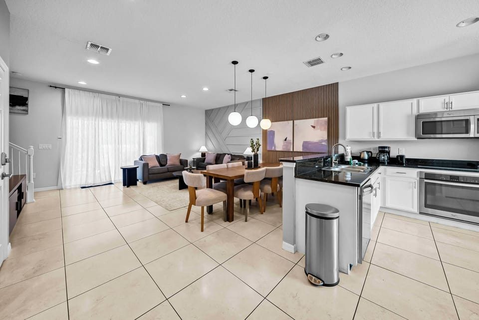 Welcome to this inviting kitchen and dining space, featuring sleek granite countertops and elegant wooden cabinetry, perfectly complemented by soft pendant lighting. The open layout encourages conversation, making meals a delight.