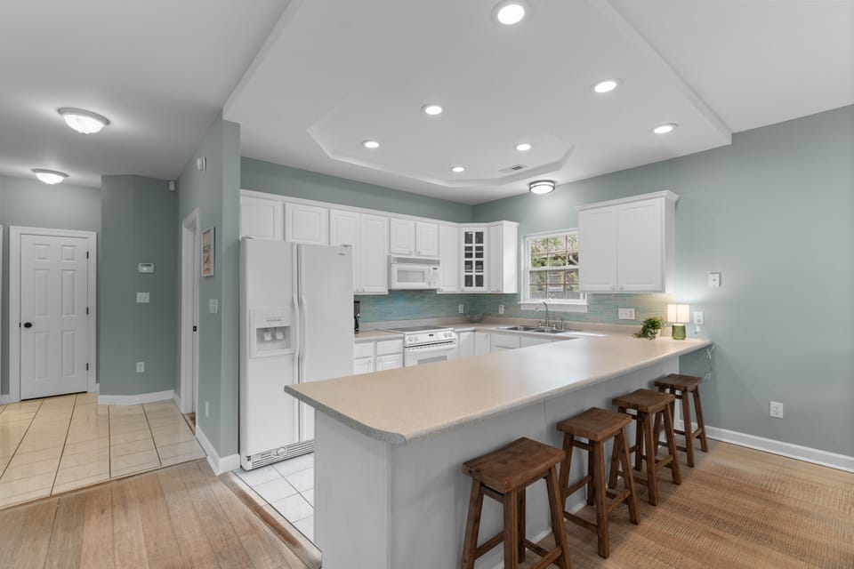 A bright, fully-equipped kitchen awaits your culinary adventures, with ample counter space, modern appliances, and an inviting breakfast bar perfect for casual meals and morning coffee.