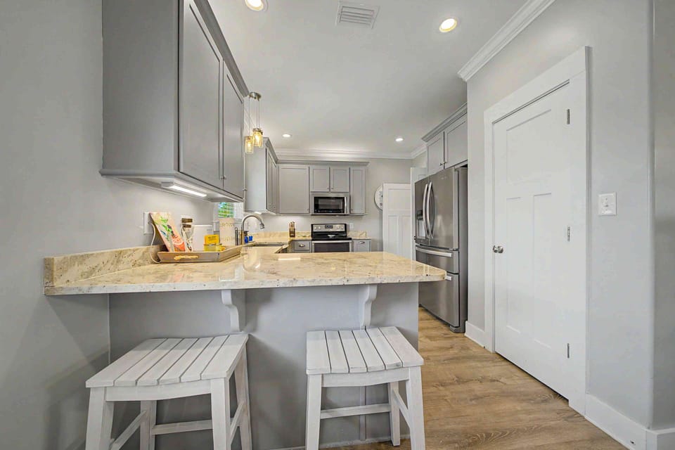Bright modern kitchen with breakfast bar, stone counters, and stainless appliances