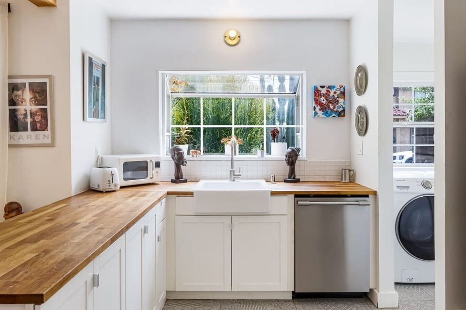 Sun-drenched kitchen with a classic farmhouse sink, butcher block countertops, and garden views — cooking here actually feels like a treat