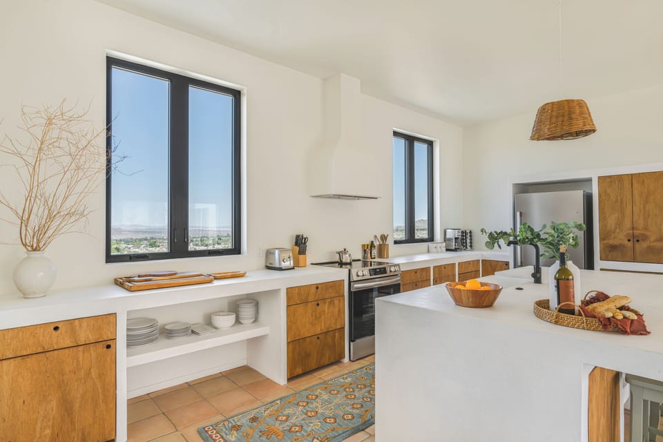 A bright, open-concept kitchen featuring warm wood cabinetry and clean white countertops.