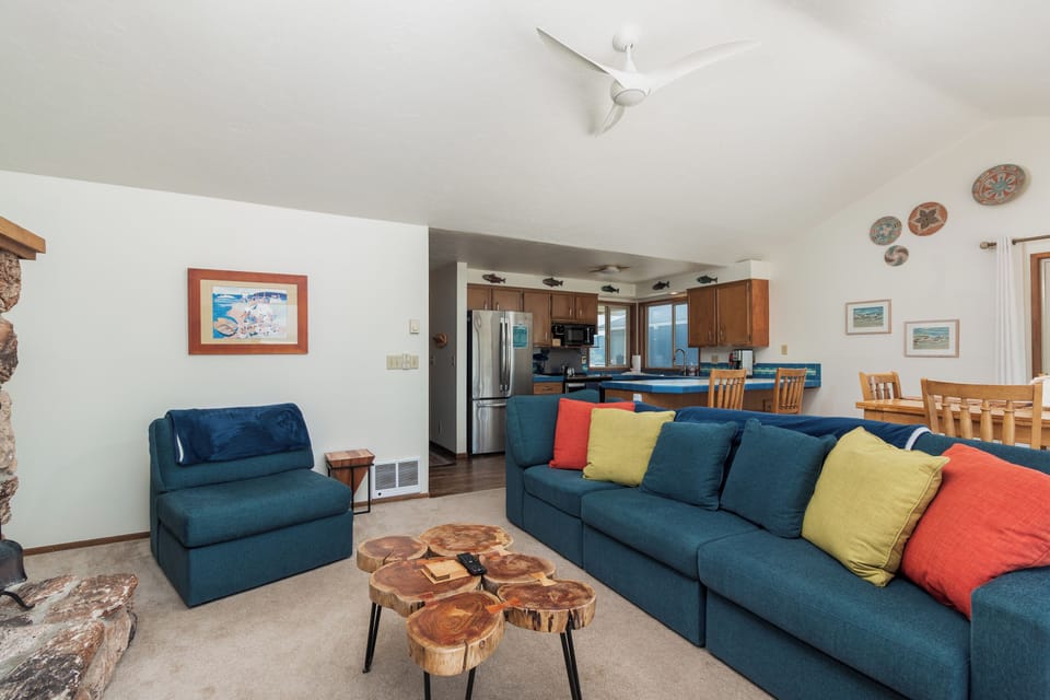 Settle into your spacious, open-concept living area where teal sofas and colorful cushions invite you to relax. The natural wood coffee table and ocean-inspired art bring warmth and charm to your lakeside retreat.