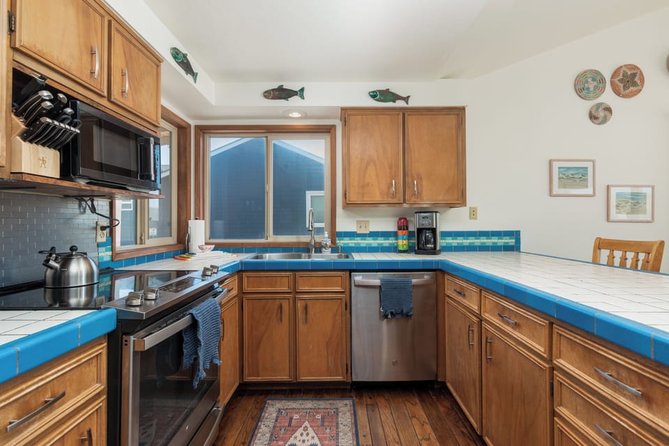 Step into your fully equipped kitchen with charming blue tile countertops, modern appliances, and coastal touches. Bright natural light fills the space, making meal prep feel effortless and relaxing.