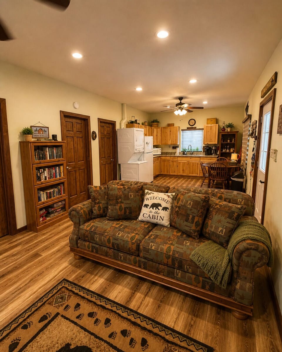 Cozy rustic cabin interior with open-concept living room and kitchen, wood flooring, lodge-style furniture, and warm lighting—perfect for vacation , mountain retreat, or countryside getaway.