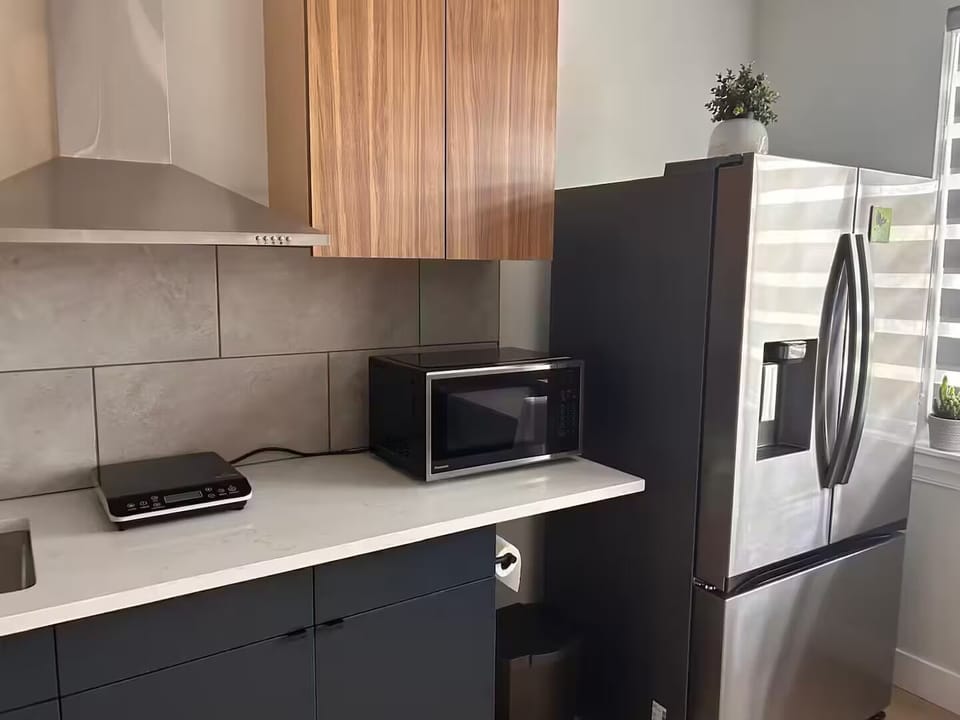 Kitchen with cooktop, microwave, and full-size refrigerator and freezer. 