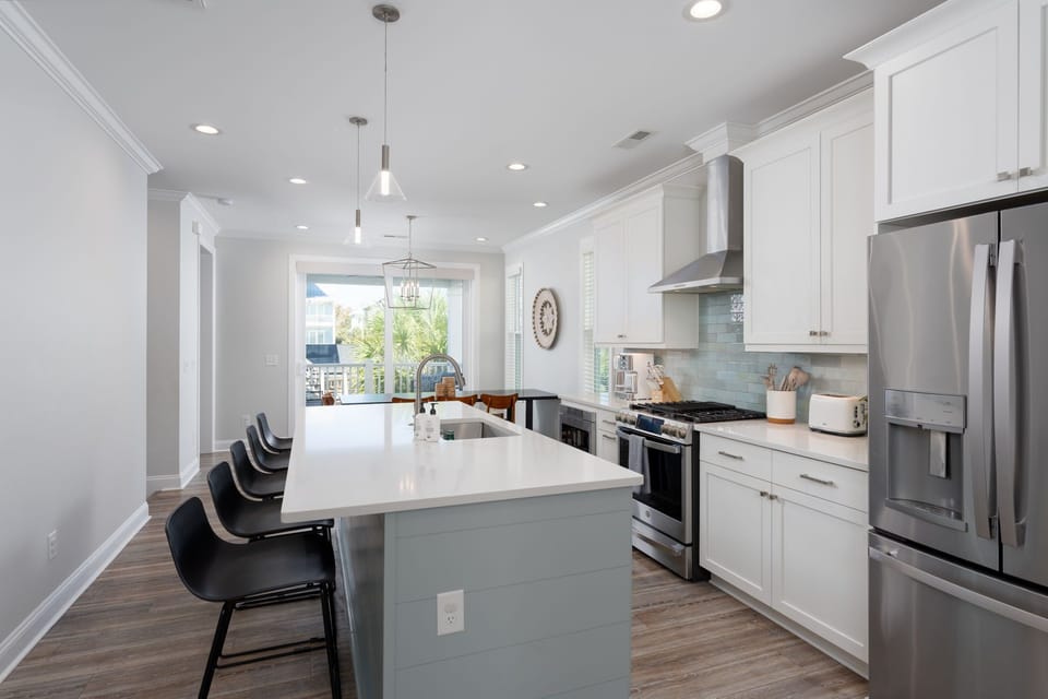 Fully stocked gourmet kitchen ready for family meals and beach snacks. An oversized island offers plenty of prep space and seating.