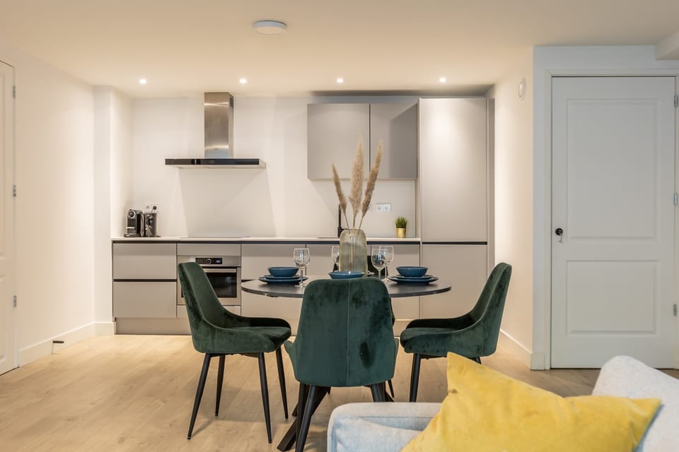 Adjacent to the living area is a round dining table for four, positioned between the kitchen and living space.