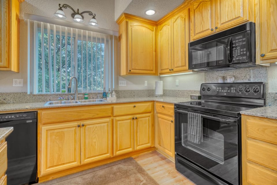 Bright kitchen with granite counters, full appliances, and sunny window view