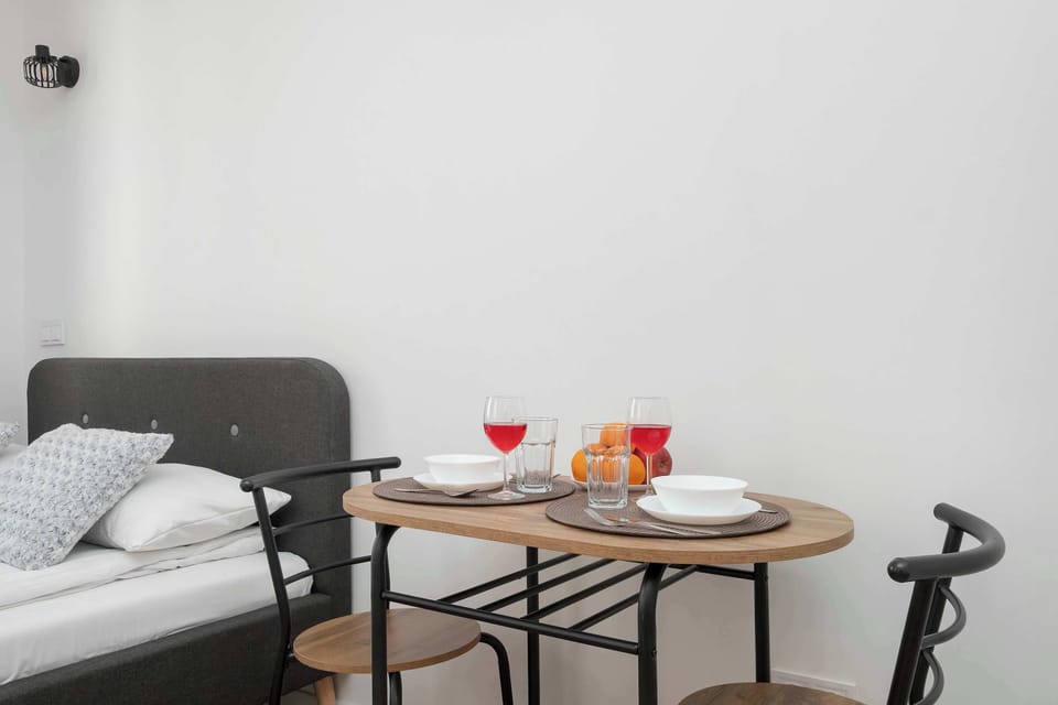 A compact dining and relaxation area with a round table set for two people. The simple design and neutral colors create a calm and cozy vibe.