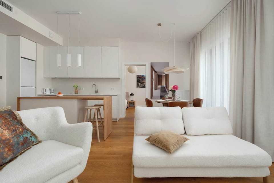 An open-plan living space with a sofa, dining table, and warm wooden flooring throughout.