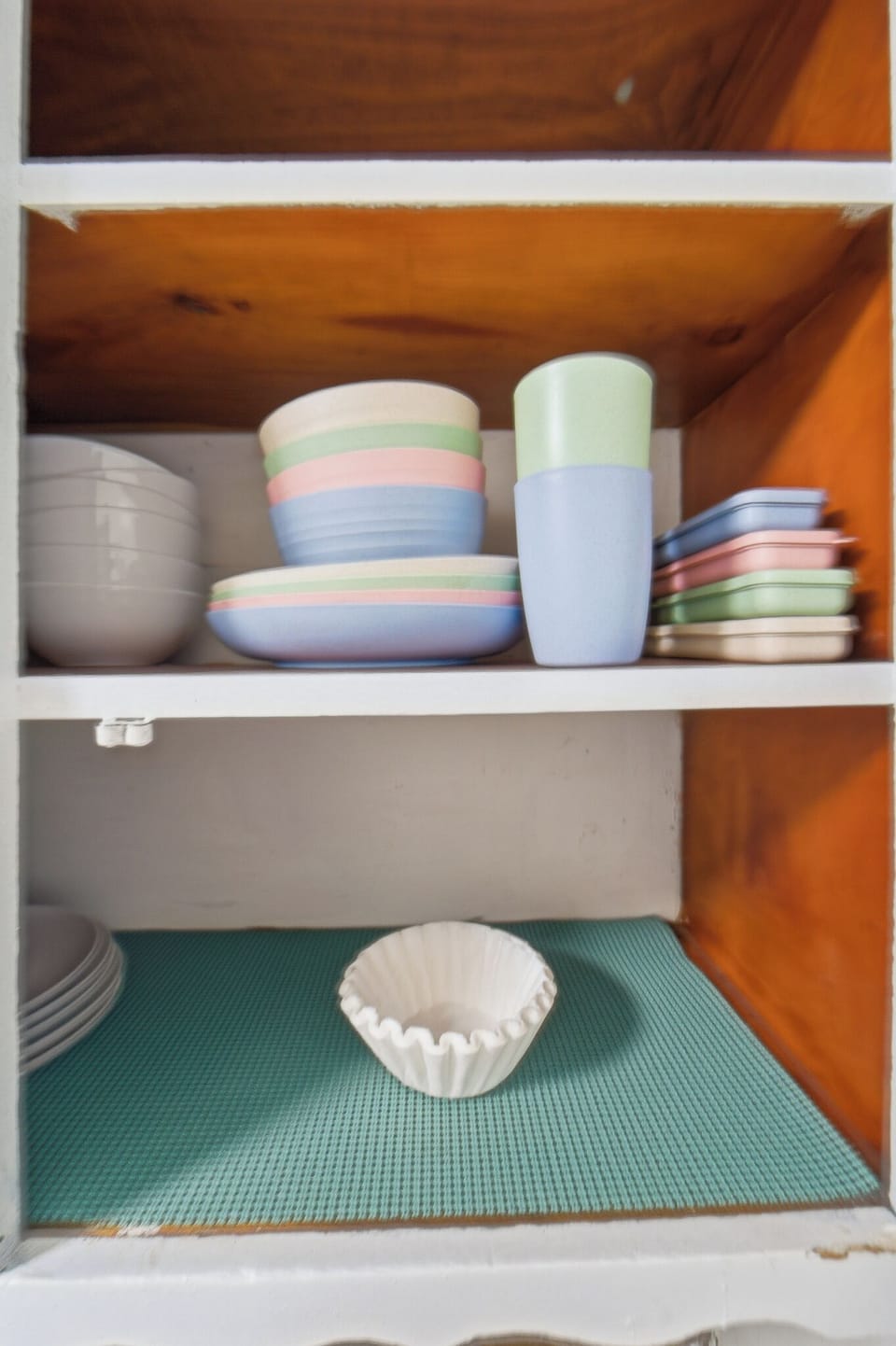 Well-stocked kitchen cabinet with cheerful pastel Children dishware 