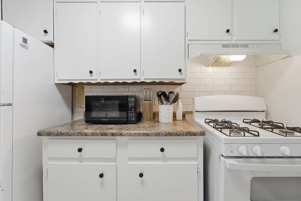 Bright kitchen with gas stove, fridge, microwave, and essentials for easy meals