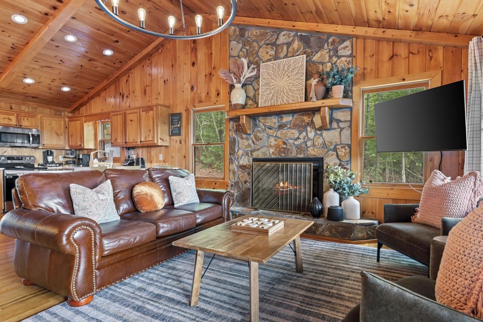 Unwind in our cozy main level living room with a crackling fireplace and breathtaking views right from the couch. Enjoy open space and comfort, where every moment feels like a peaceful escape.