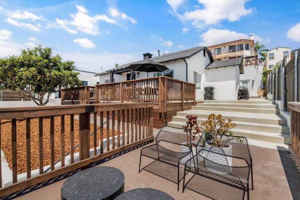 A beautifully landscaped back property featuring modern mesh lounge chairs, tiered wooden decks, a private grill station, and plenty of room to soak up the sun.