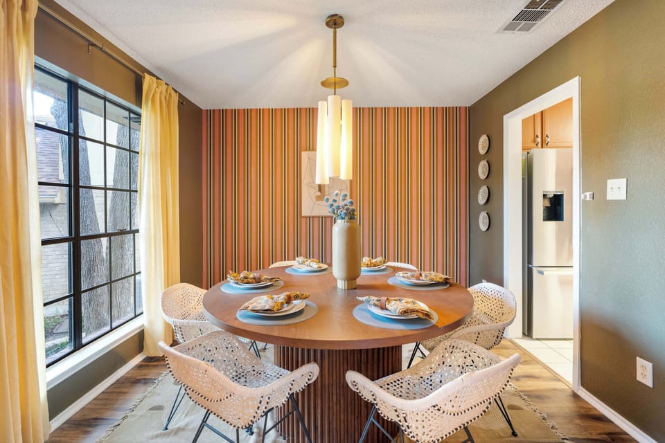 Dine in style — this retro-chic dining room seats the whole crew in designer chairs, with bold striped walls and warm pendant lighting setting the perfect mood.